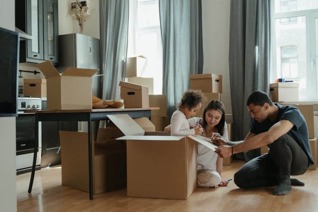 Free A family unpacks moving boxes in their new home kitchen, creating a cozy atmosphere. Stock Photo