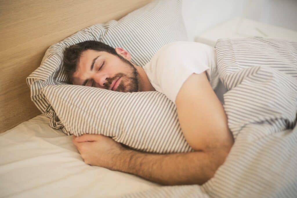 Man sleeping peacefully on striped bedding, embracing relaxation and comfort. Stock Photo