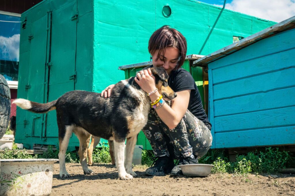 A woman at a shelter holding a dog and wondering, “How long does it take to adopt a dog?