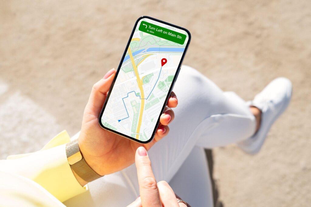 Close-up of a woman holding a smartphone with GPS navigation and a location pin on the screen.