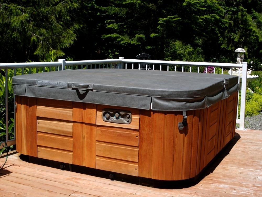 Outdoor wooden hot tub with a gray cover on a wooden deck