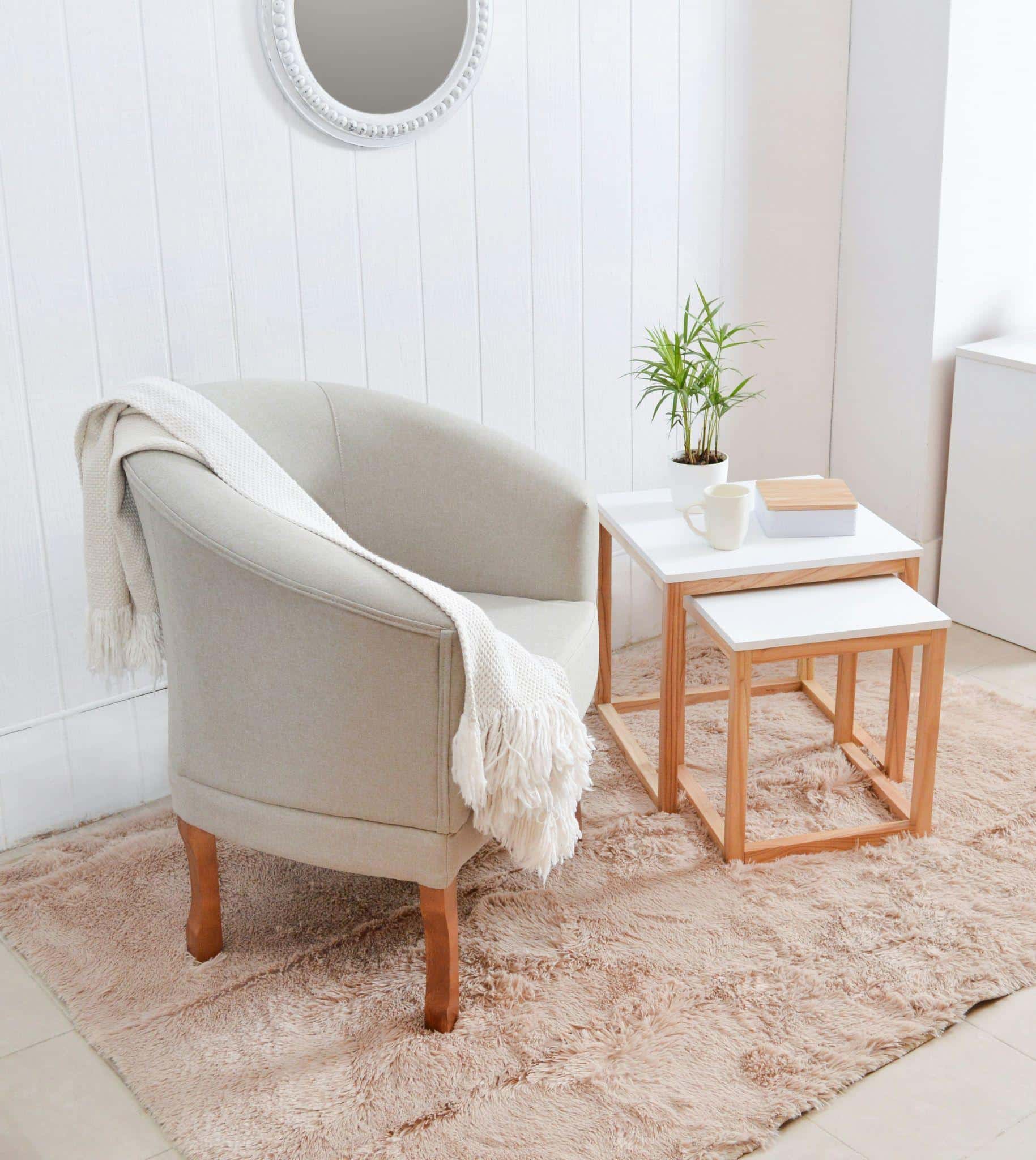 Chic shaggy rug in the corner of the living room decorated in coastal style with natural materials and white walls.