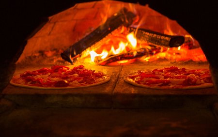 classic Italian pizzas being cooked in a traditional wood-fired oven