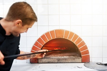 a chef using a commercial pizza oven