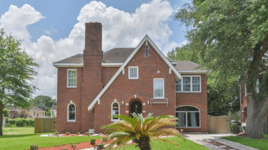 Beyonce's childhood home with a prominent chimney, white trim, and a sago palm in the foreground