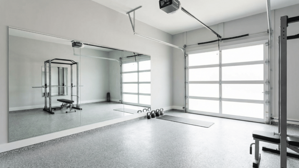 Bright half garage gym with light gray walls, large mirror, compact rack, and open center space