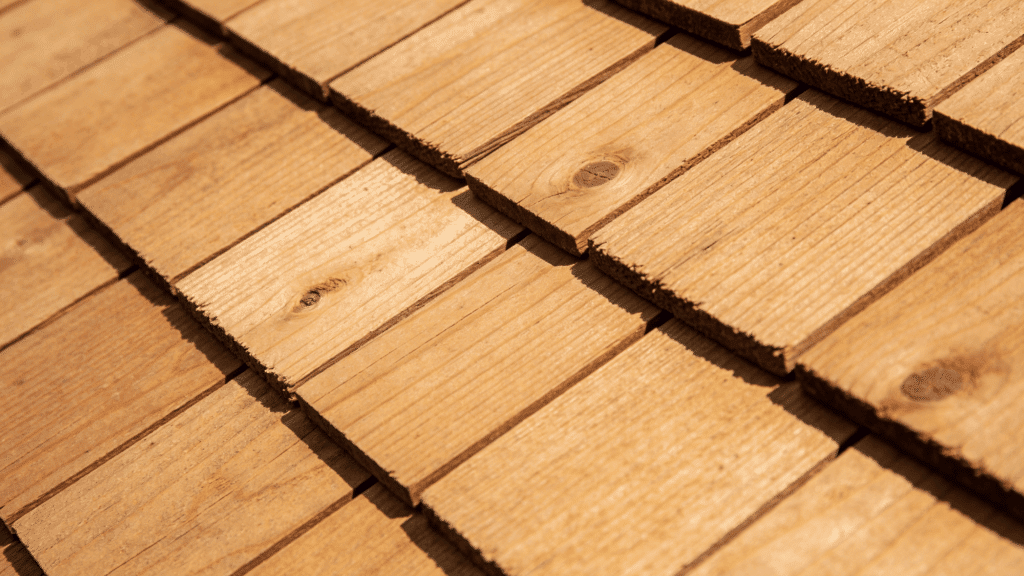 Close-up view of overlapping, textured, medium-brown cedar wood roof shingles.