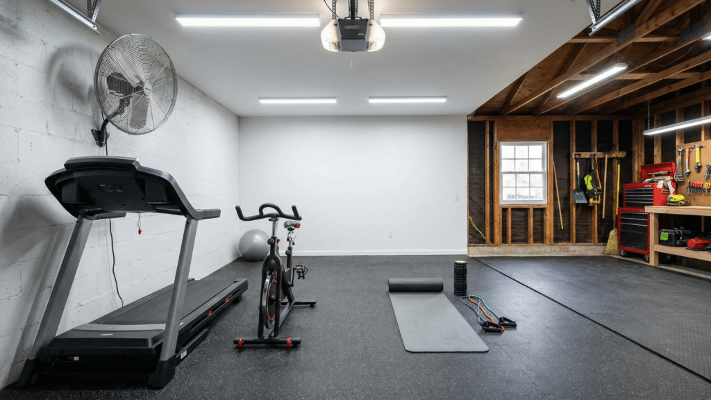 Half garage gym with treadmill and spin bike aligned along one wall and open stretch area in the center