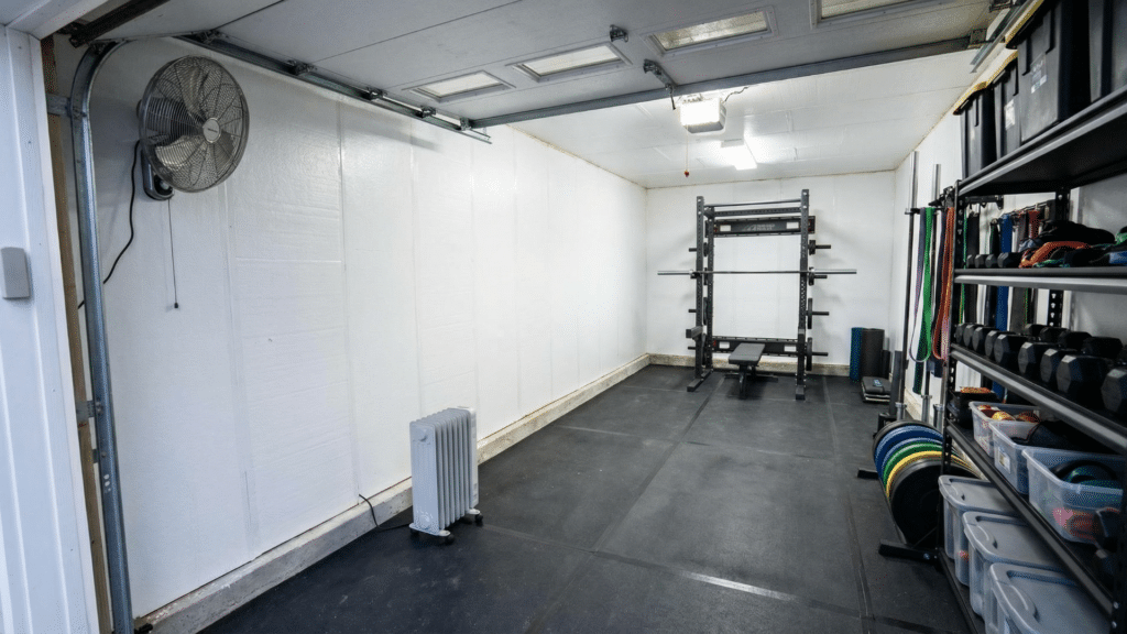 Insulated half garage gym with rack positioned away from garage door and ventilation equipment installed