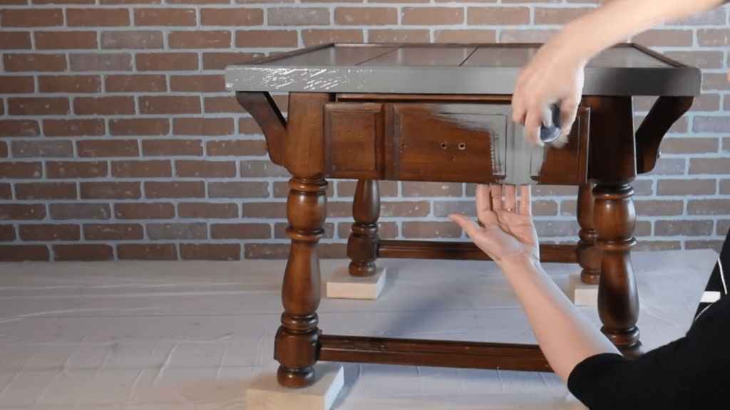 Applying first coat of chalk paint to a wooden table with a brush