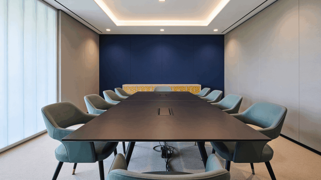 a modern conference room with a long table surrounded by chairs and soft lighting in a clean minimalist office space