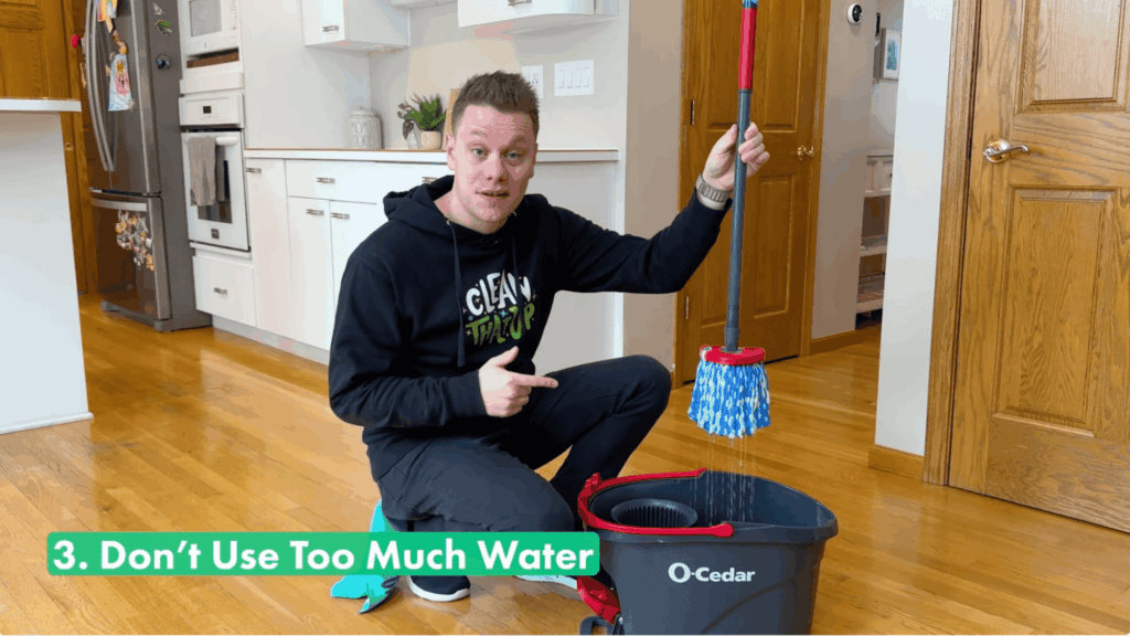 a person pointing to a dripping wet mop over a bucket showing how too much water can damage wood floors