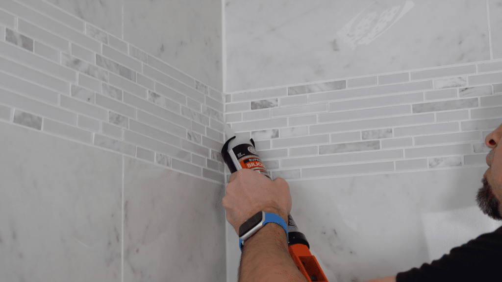 applying caulk in corner joints of bathtub wall