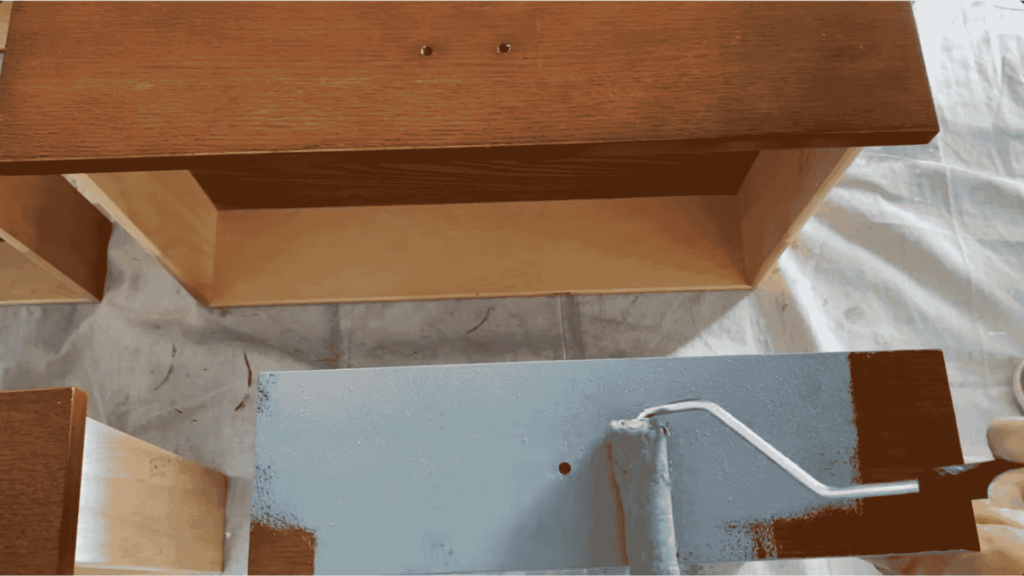applying first coat of paint on drawer using roller during how to paint furniture step by step guide