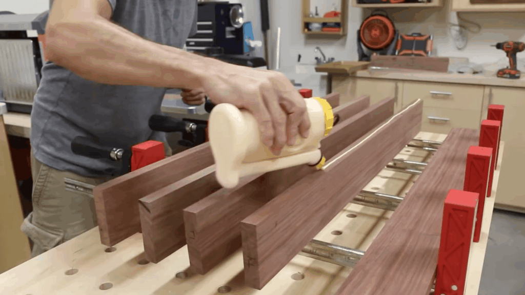 applying wood glue evenly on panels and clamping boards together for diy end table assembly process