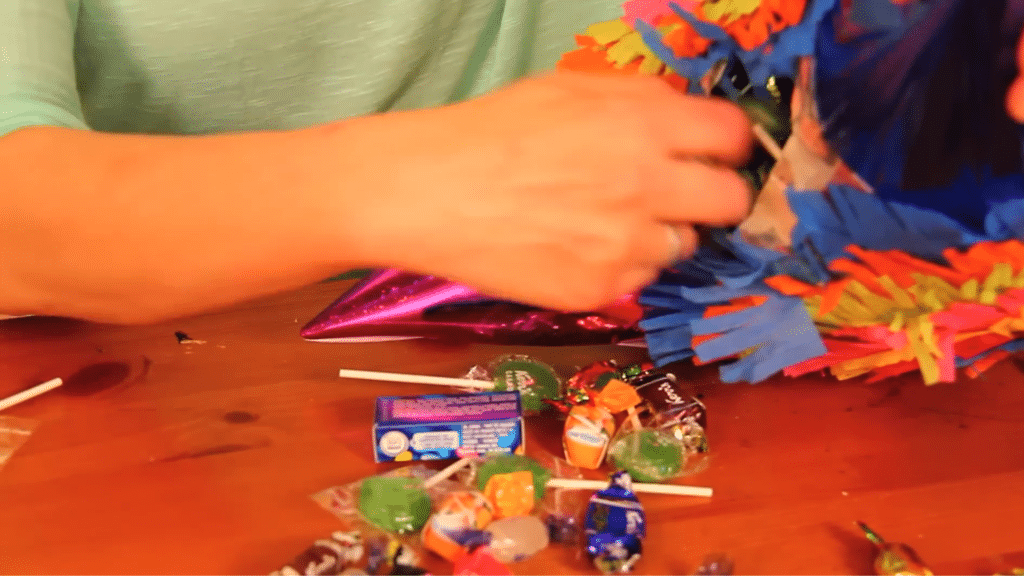 assorted candies spilling from finished pinata on wooden table surface