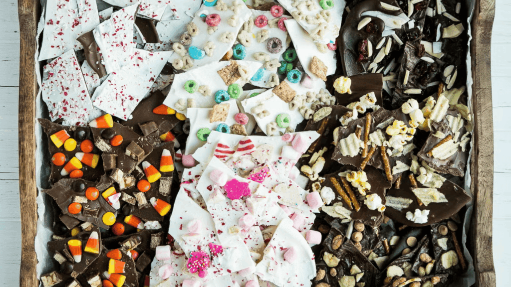 assorted chocolate bark pieces with candies cereal pretzels and nuts arranged in wooden tray for homemade gifts made easy