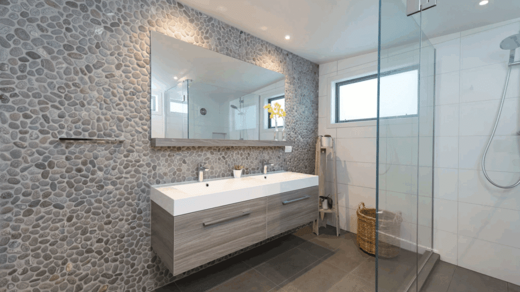 bathroom with pebble stone accent wall floating double sink vanity and glass shower in clean minimalist japanese bathroom design