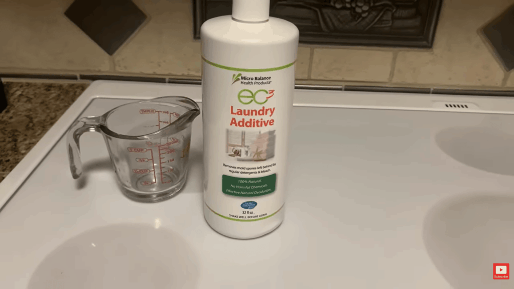 bottle of laundry additive and measuring cup on counter showing product used in how to remove mold from fabric cleaning process