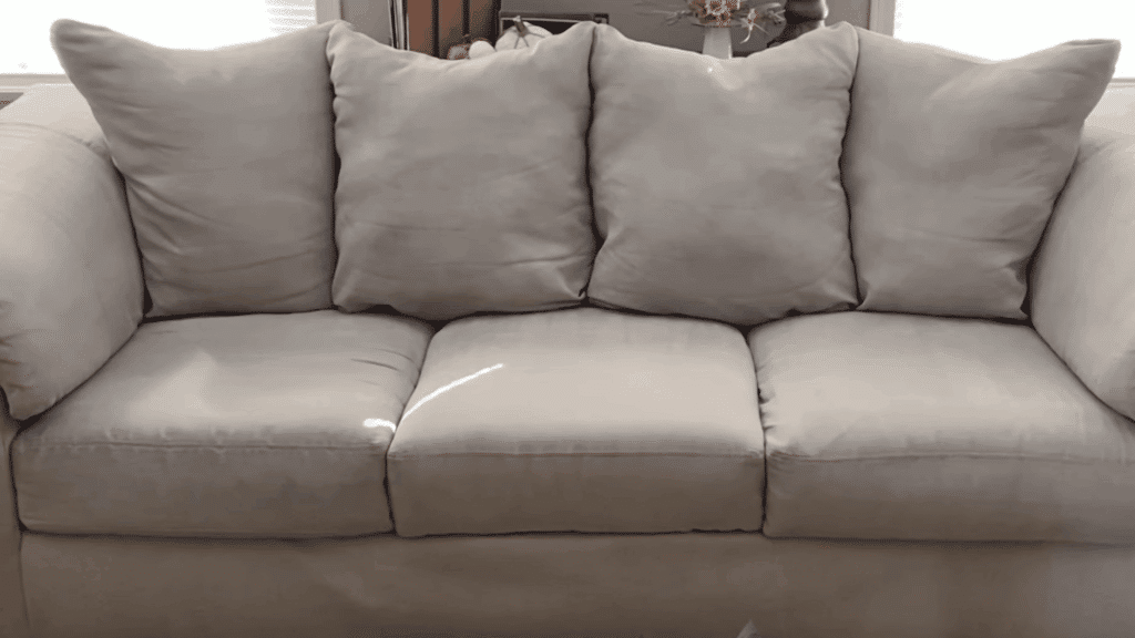 clean gray sofa with cushions arranged neatly after cleaning in bright living room