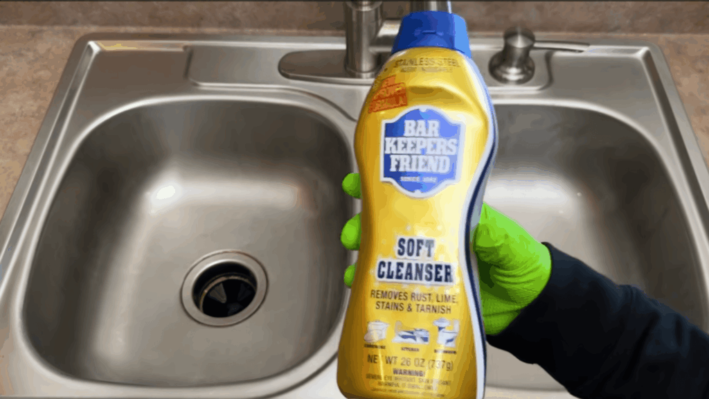 clean stainless steel sink with cleaning product bottle in hand showing polished surface result