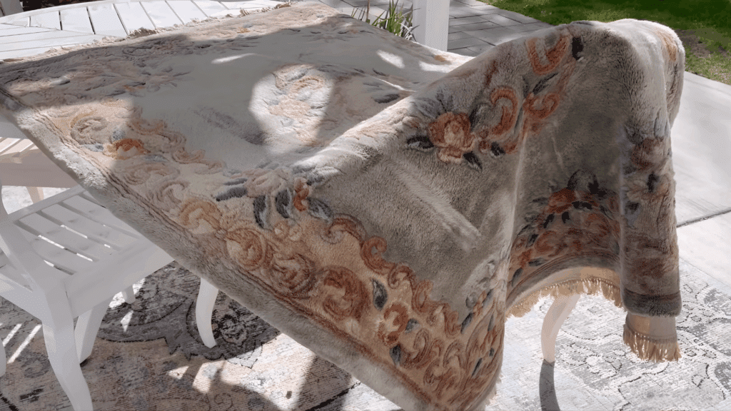 clean wool rug draped over outdoor table drying in sunlight after washing showing how to clean a wool rug and air dry properly