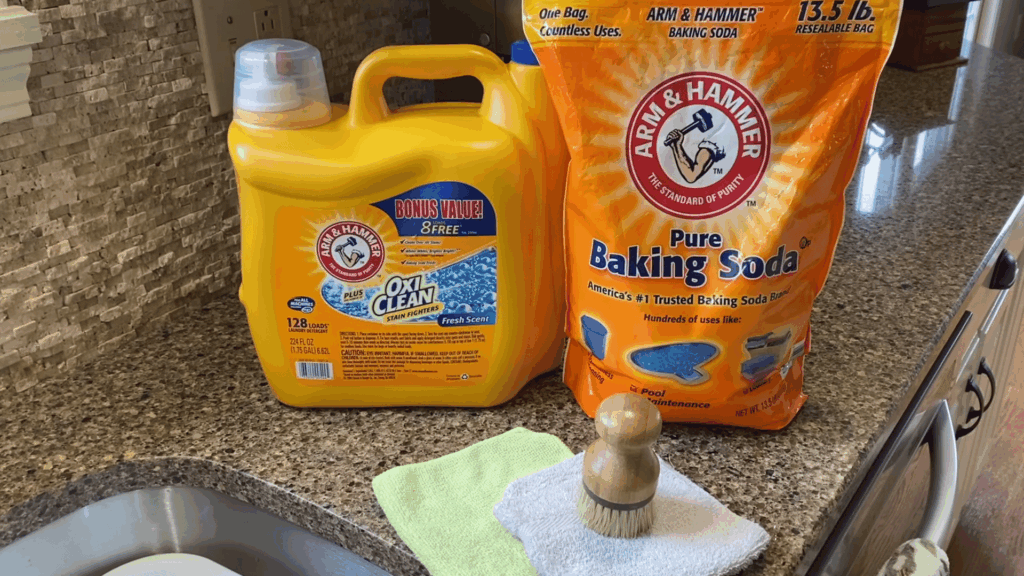 cleaning supplies including baking soda detergent brush and cloth arranged on kitchen cou