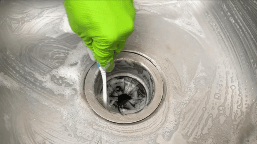 close view of sink drain being cleaned with brush and foam removing dirt and buildup