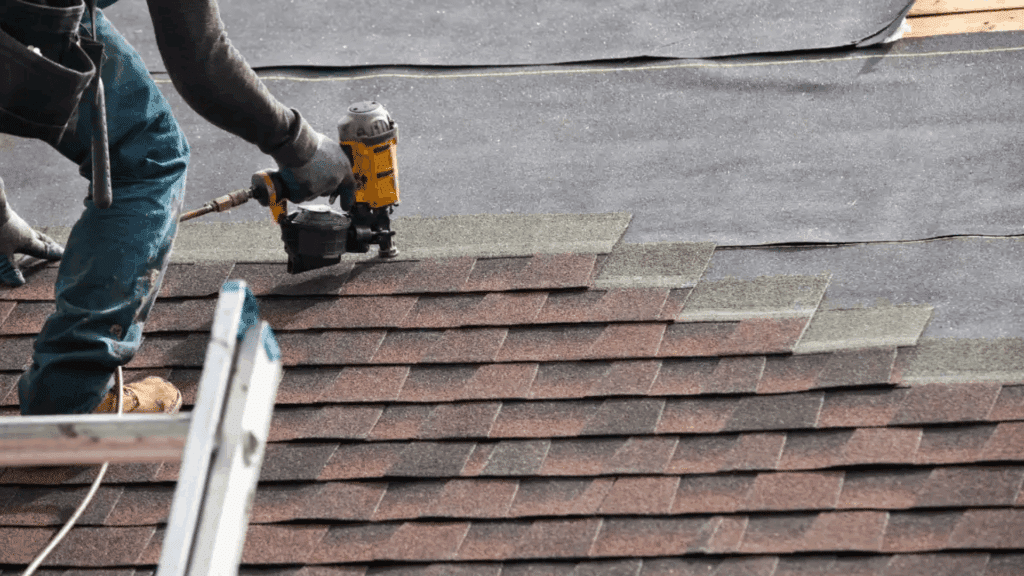 contractor installing asphalt shingles on a house roof during replacement showing how much is a new roof installation process