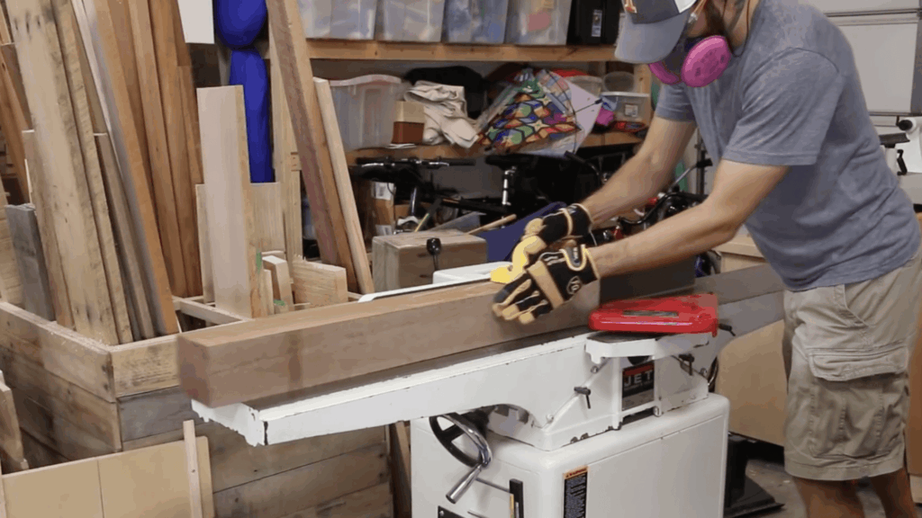 cutting and flattening wood beam on jointer machine in workshop for diy end table build project