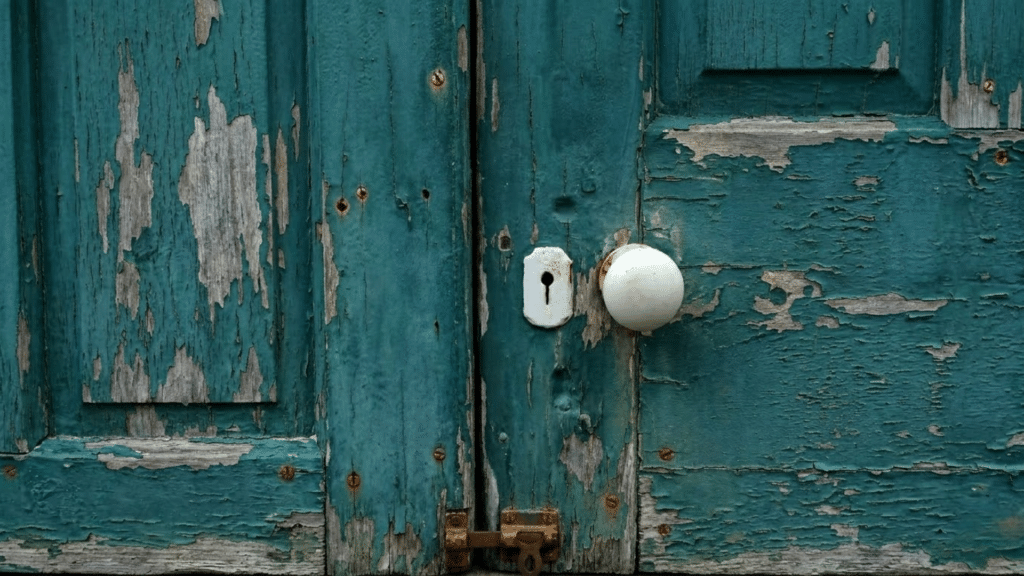 Easy Ways to Remove Peeling Paint at Home door with peeling paint being removed revealing wood underneath during home repair