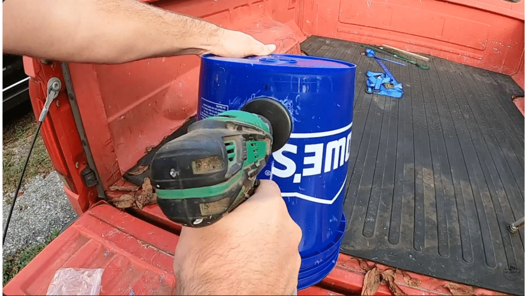 drilling a clean hole into a blue bucket using a hole saw to prepare openings for chicken feeder ports