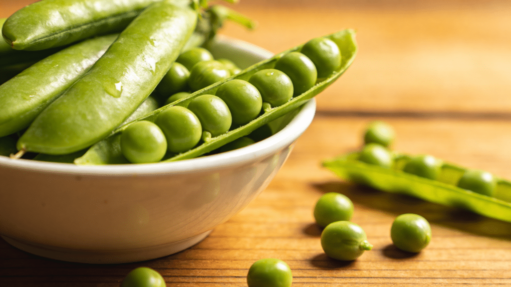 fresh green peas in pod on wooden table