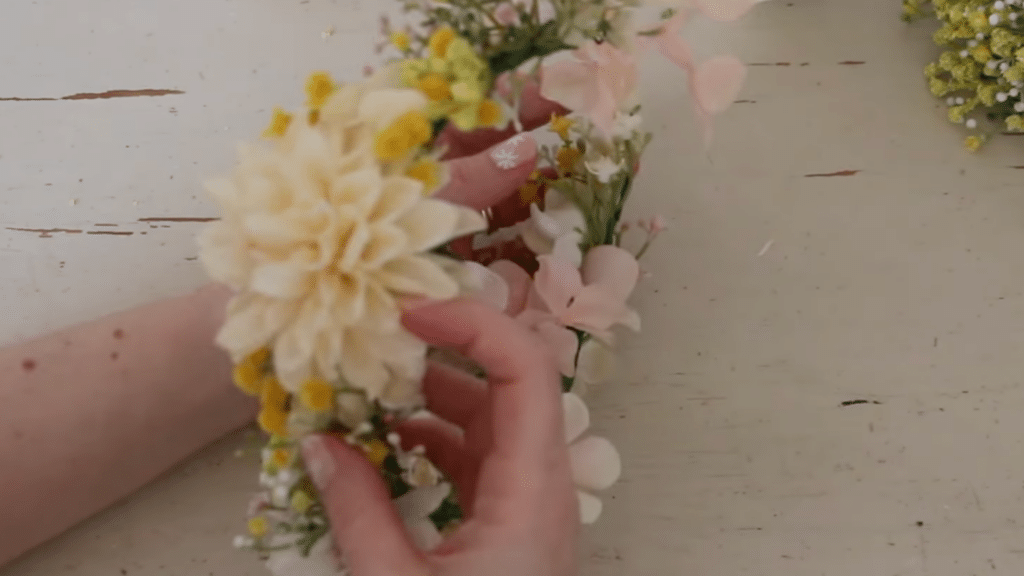how to make a flower crown by adding large and small flowers to the crown base with tape