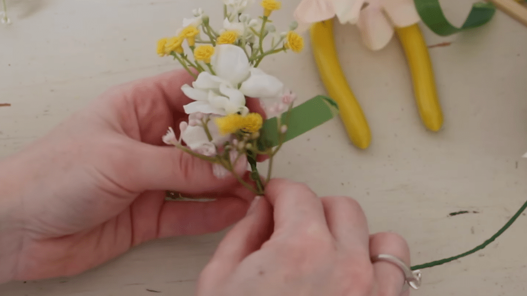 how to make a flower crown by adding white and yellow flowers to the crown base with tape
