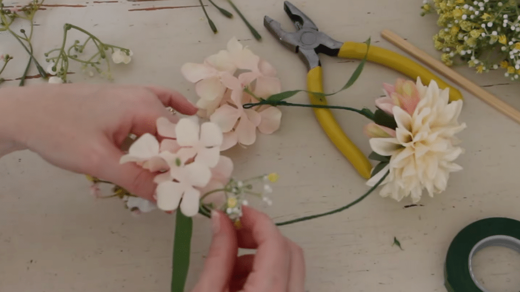 how to make a flower crown by arranging soft pink flowers and securing them with tape