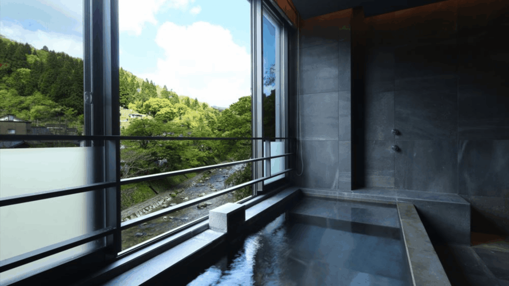 japanese bathroom design with indoor soaking tub beside large window overlooking mountain river view and modern spa style interior