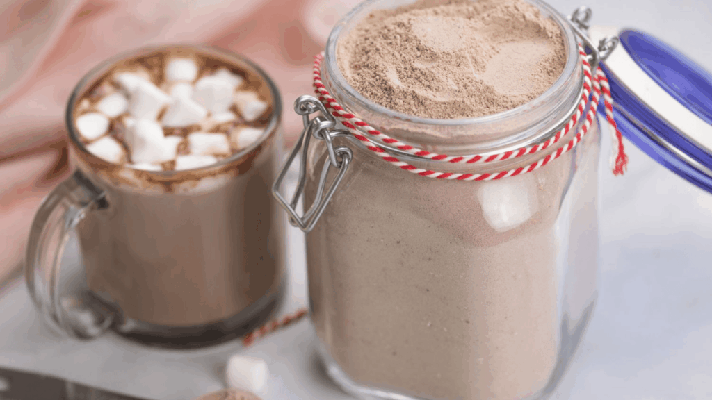 jar of hot chocolate mix beside mug topped with marshmallows and spoon on table for homemade gifts made easy