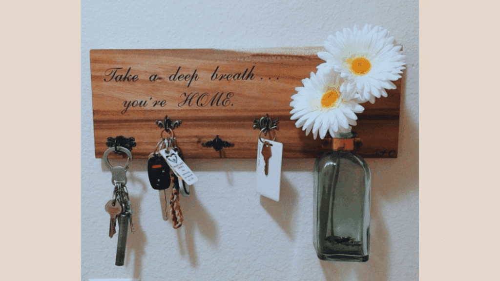key holder with a sign that says take a deep breath you're home and flowers in a bottle