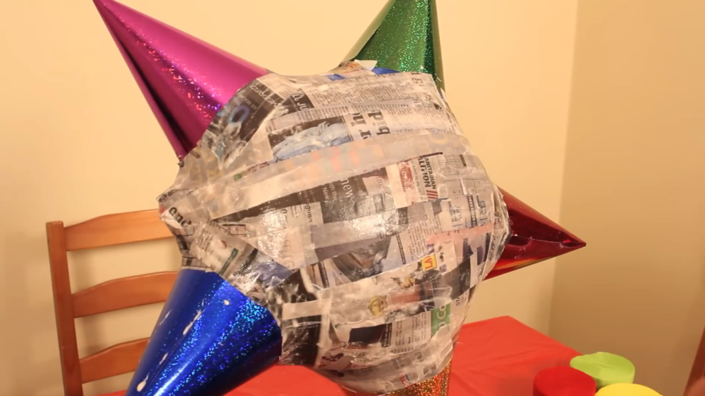 large star pinata covered in newspaper drying on table near chair