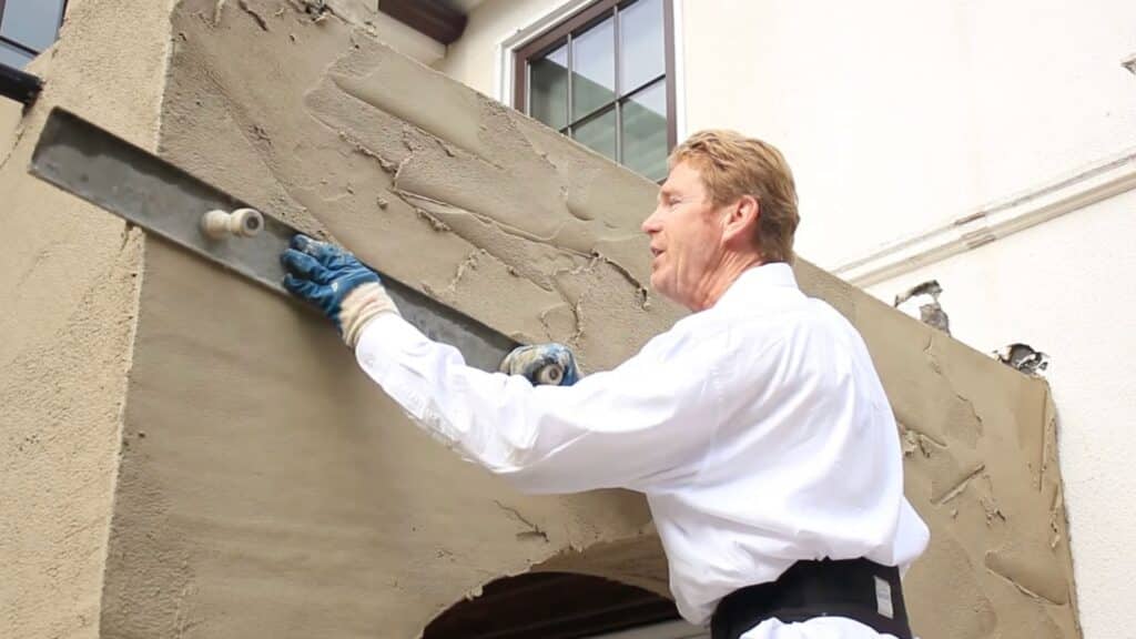 leveling brown coat stucco with darby tool to create smooth wall surface