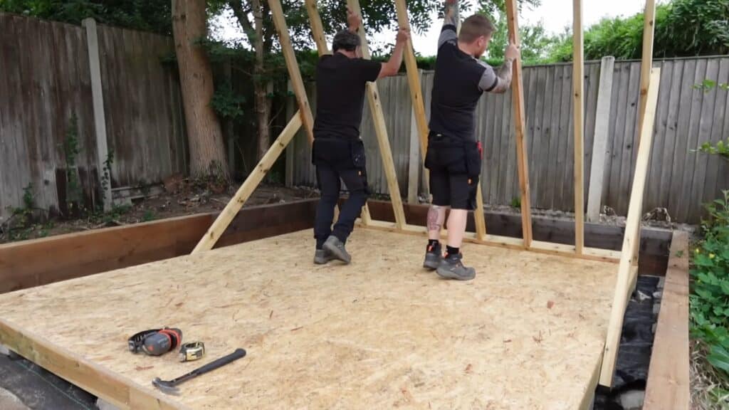 lifting the completed wall frame carefully and positioning it correctly on the shed base