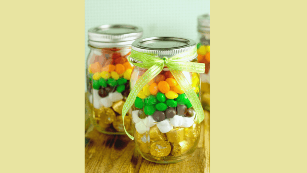 mason jars filled with colorful candy layers and tied with a green ribbon