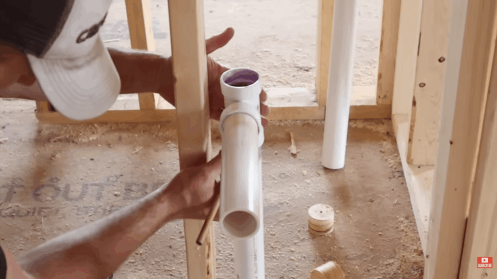 person installing pvc pipe in wall frame showing how to plumb a bathroom