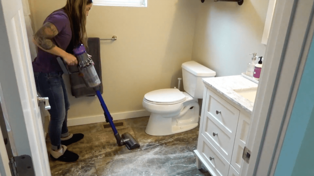 person vacuuming bathroom floor for quick cleaning