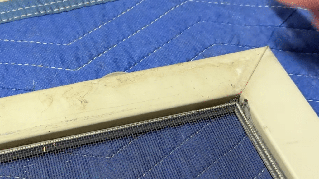 prepare the screen door by laying frame flat and removing worn mesh from corner groove before installing new screen