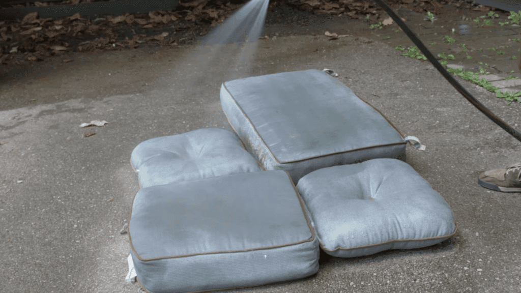 rinsing outdoor cushions with water to remove loose dirt dust and debris before deep cleaning