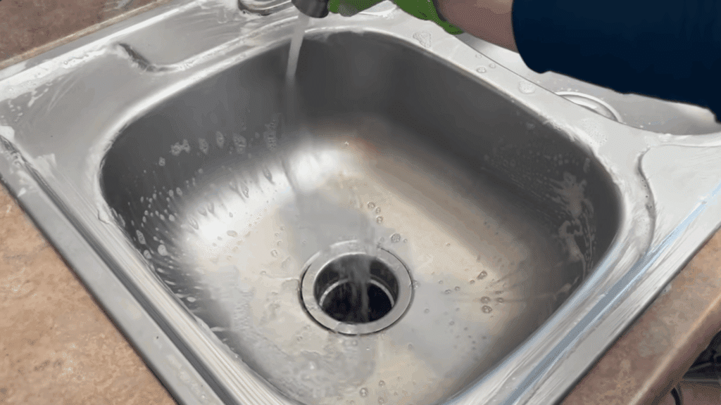 rinsing stainless steel sink with water removing soap and residue leaving clean surface