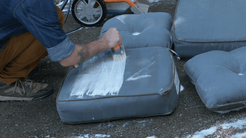 scrubbing stains then rinsing cushions with pressure washer to remove dirt and soap