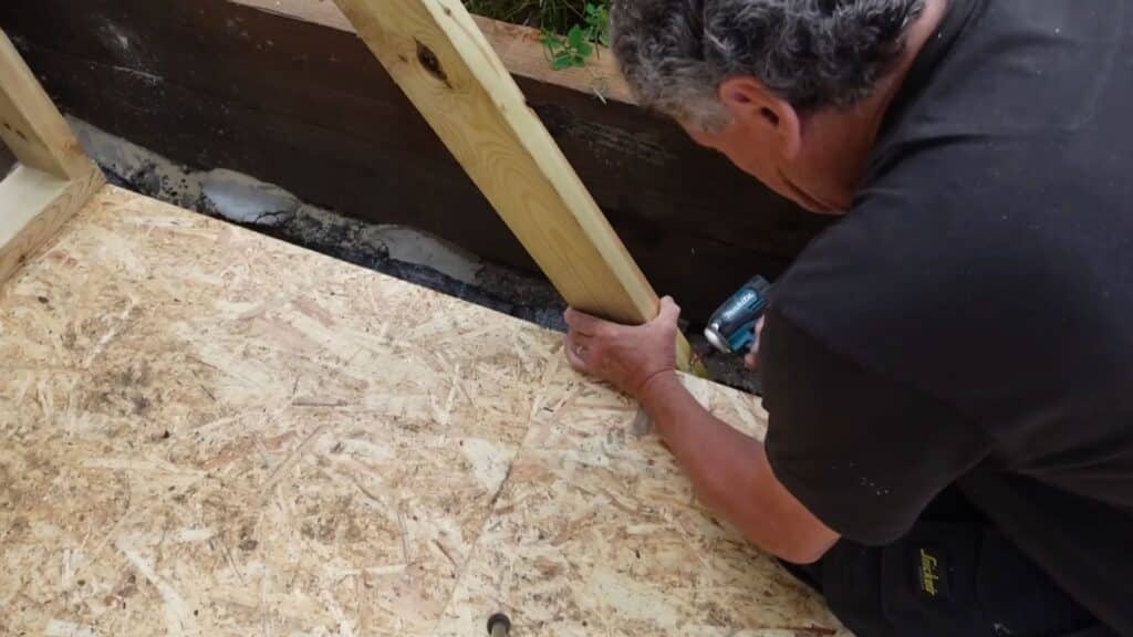 securing the wall firmly to the base using screws to keep the shed stable and aligned